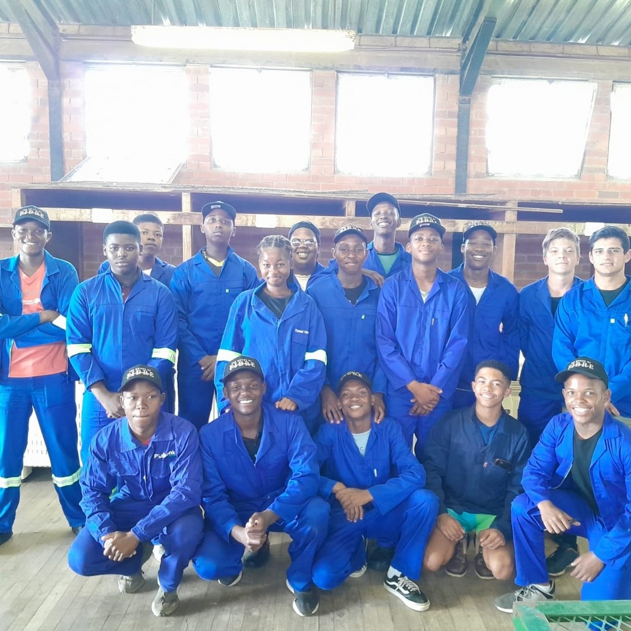 Group of students in blue uniforms posing indoors at a Mohair Classing training workshop.